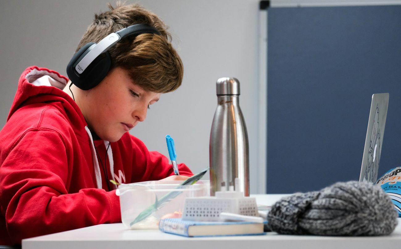Un élève du secondaire avec un casque d'écoute fait ses exercices